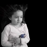 Petite fille en noir et blanc faisant un calin a son petit doudou bleu
