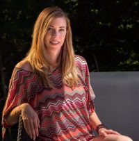 Femme assise habillée d'une tunique bariolée et d'un short