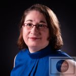 Portrait Corporate 16/9ème pour projet numérique et impression photographie corporate de femme au tee-shirt col américain et avec des lunettes