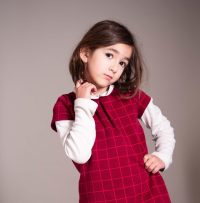 petite fille pensive habillée d'une robe rouge et d'un caleçon noir